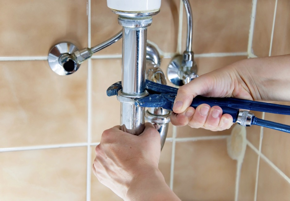 Plumber using wrench to repair leaking bathroom sink pipe in Dayton OH